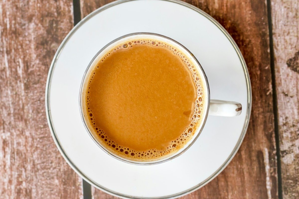 Eine Tasse Chai mit Milch auf einer weißen Untertasse, von oben