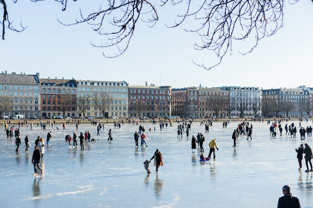 Viele Menschen auf einer Eisfläche unter freiem Himmel vor einer Häuserzeile