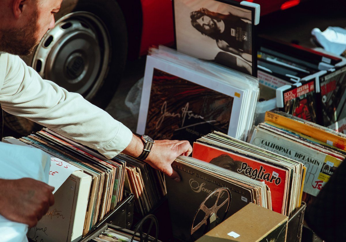 Hände blättern in einer Kiste mit Schallplatten auf einem Flohmarkt