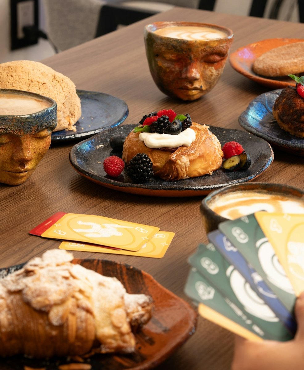 Spielkarten, Kuchen und Tassen auf einem Cafétisch