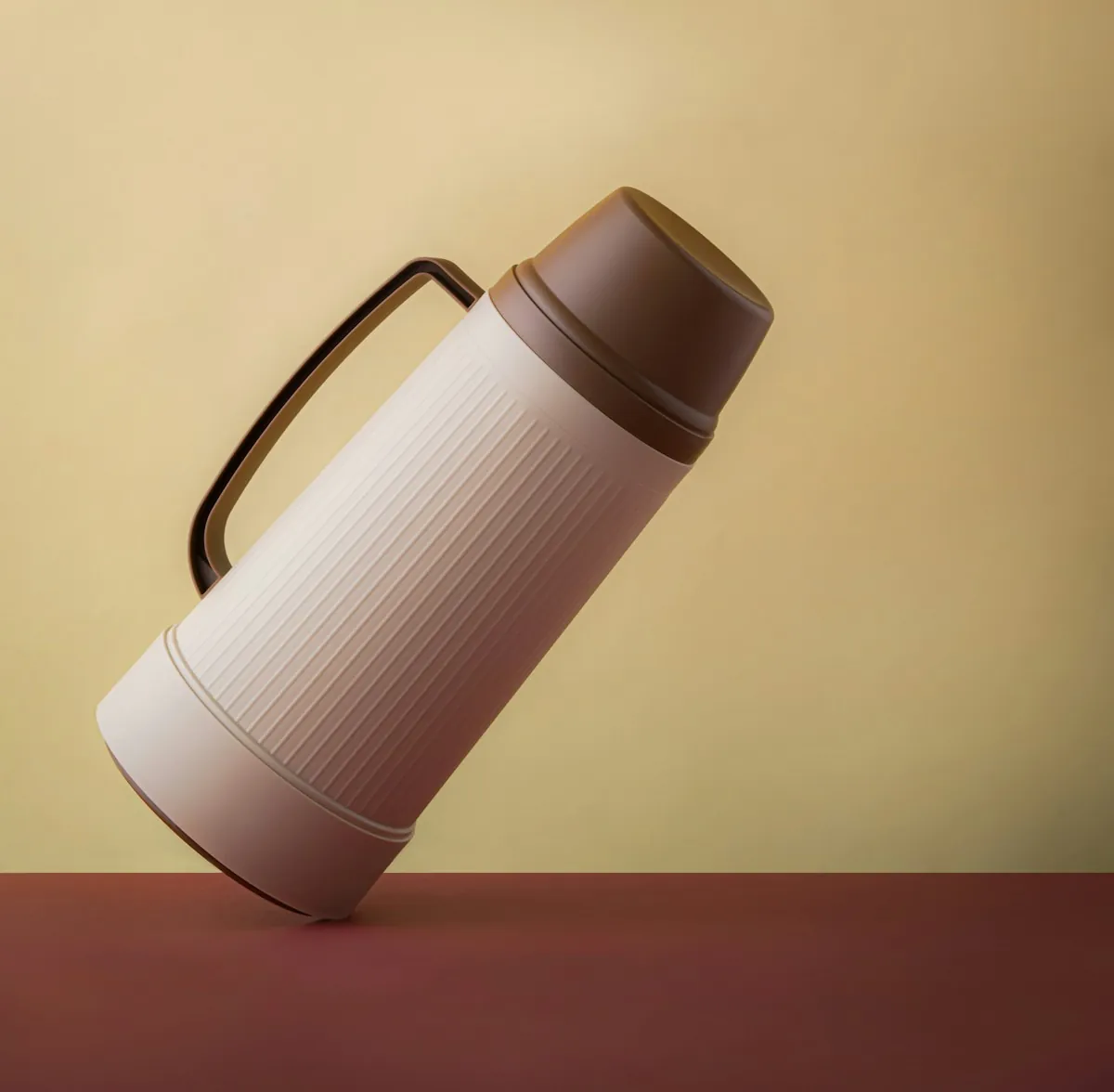 Eine helle Thermoskanne mit Henkel vor gelbem Hintergrund