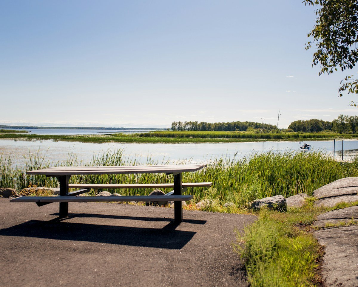 Ein hölzerner Picknicktisch am Ufer eines Sees im Abendlicht